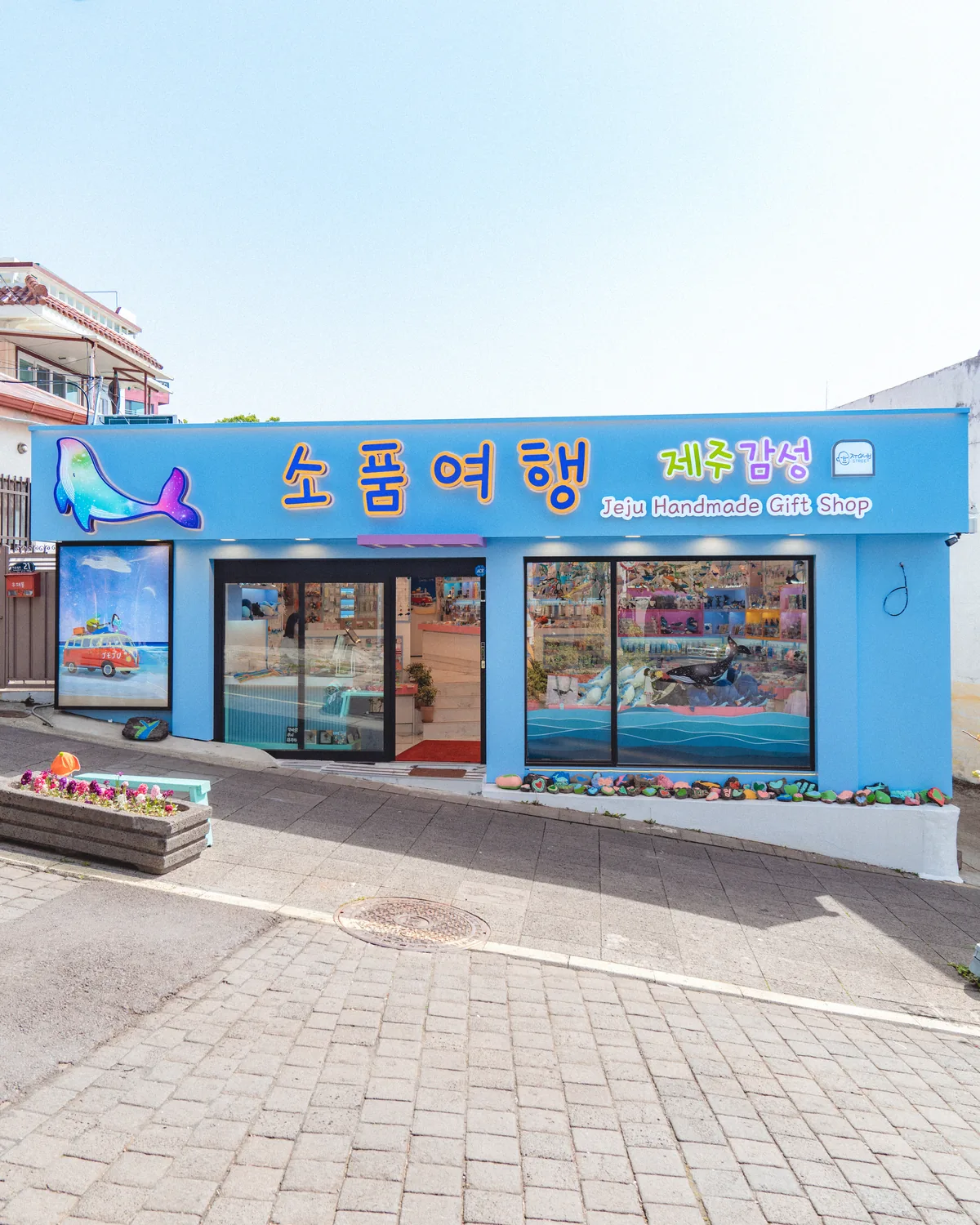 파란 하늘 아래 하늘색 외벽에 소품여행 간판이 걸린 매장 외관
